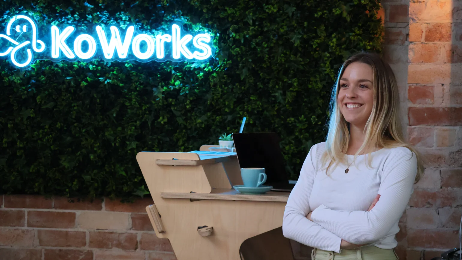 Woman standing next to sign in KoWorks coworking space