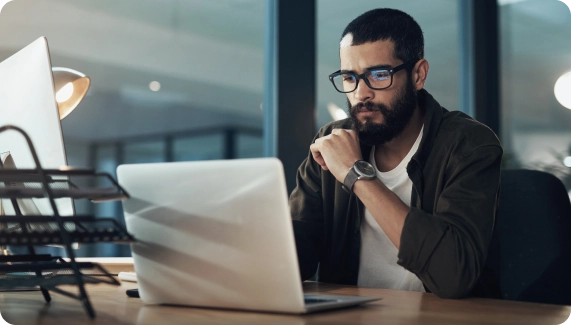 Coworking space operator focused on laptop at modern shared workspace — representing the challenges of managing operations manually and the benefits of automating with Optix