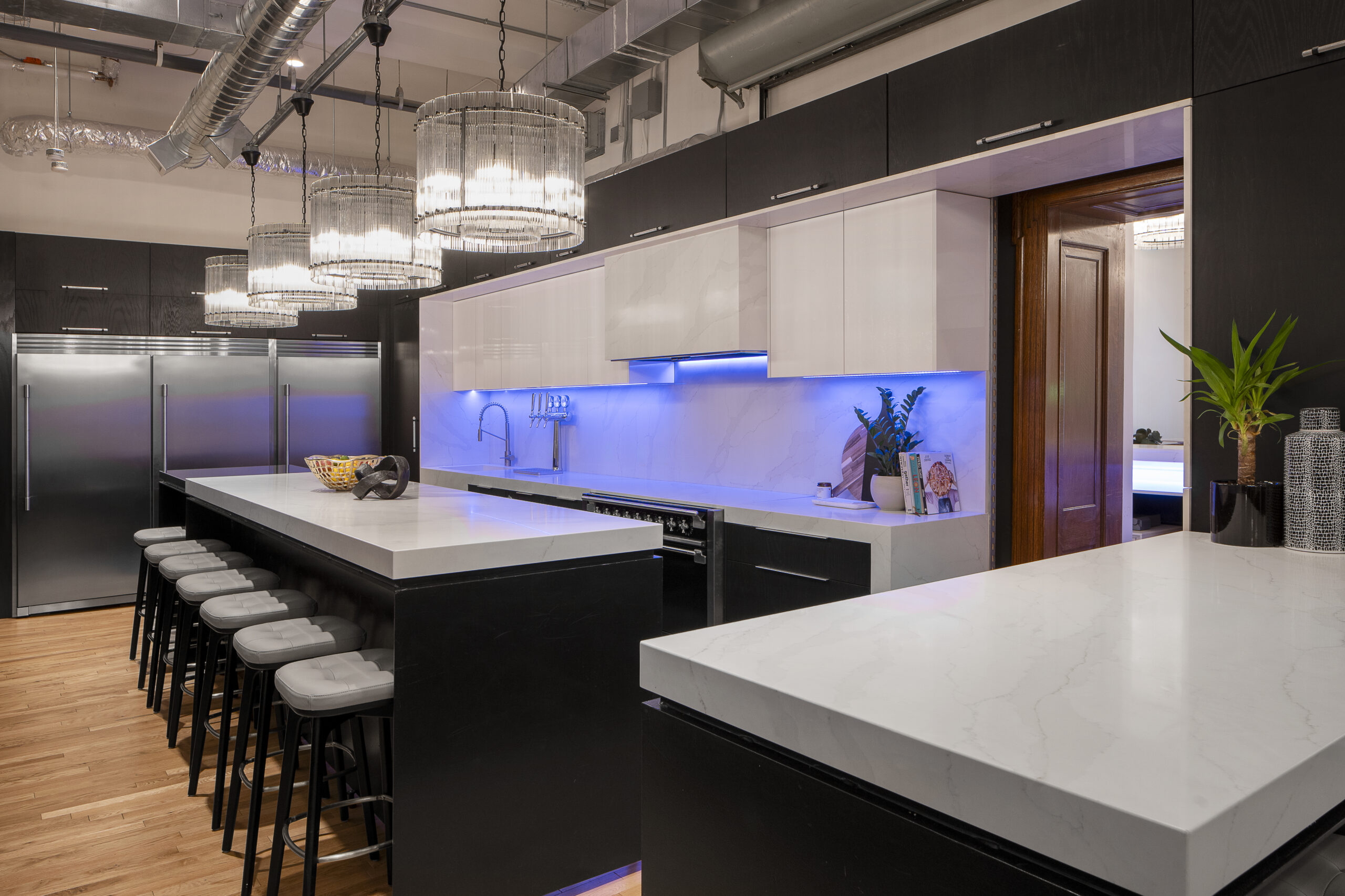 The Den 1880 kitchen, with a marble island, bar stools and a backlit splashback