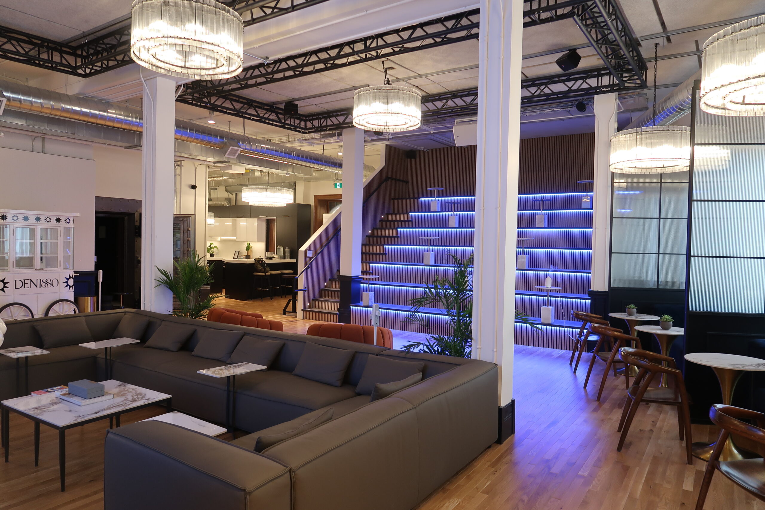 The Den 1880 main lounge, with sofas, cafe tables and the lit tiered seating behind